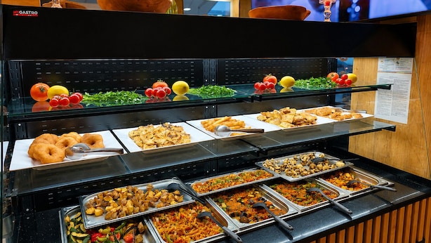 A buffet with various food options, including fruits, vegetables, and pastries.