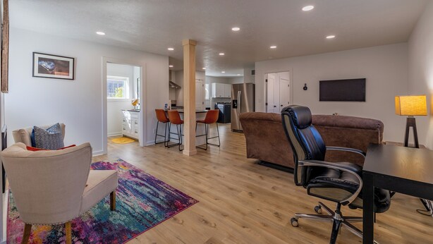 A modern living room with a sofa, a chair, a desk, and a colorful rug. - Chic Downtown Cody Hideaway (Cody)