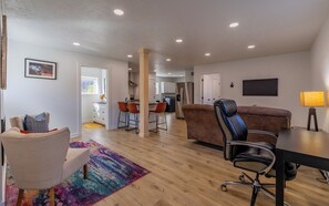 Un salon moderne avec un canapé, un fauteuil, un bureau et un tapis aux couleurs vives.