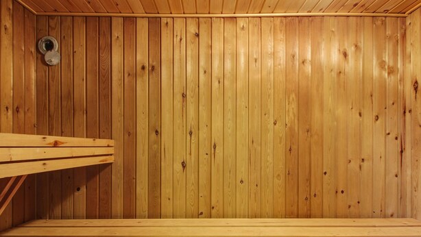 En träbeklädd bastu med en bänk och ett ventilationshål.