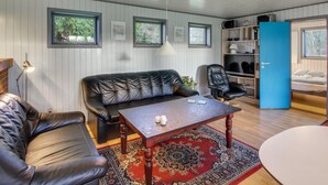 Ett mysigt vardagsrum med en soffa i läder, ett soffbord i trä och en blå dörr som leder till ett sovrum.