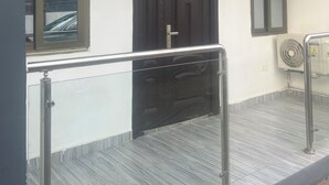 A building entrance with a dark wooden door, a window, and a metal handrail. - CANA Unique Flats (Kwabenya)