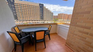 Varanda com uma mesa redonda e quatro cadeiras, parede de tijolos e vista para um edifício de hotel.