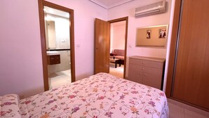 Quarto com cama, guarda-roupa, espelho e ar condicionado.
