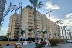 A multi-story building with balconies, surrounded by palm trees and street lamps. - ACV - Aguamarina-2ª linea planta 4 sur (OROPESA)