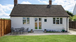 A house with a tiled roof, a front door, and a small patio with a table and chairs.