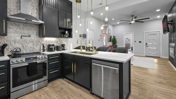 A modern kitchen with a built-in oven, a dishwasher, and a large island with a sink. - New Indy Game House- Theater + Arcade - Sleeps 12 (Indianapolis)