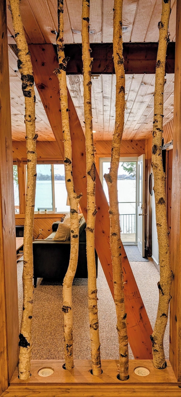 A wooden interior with birch tree trunks, a sofa, and a view of the outdoors.