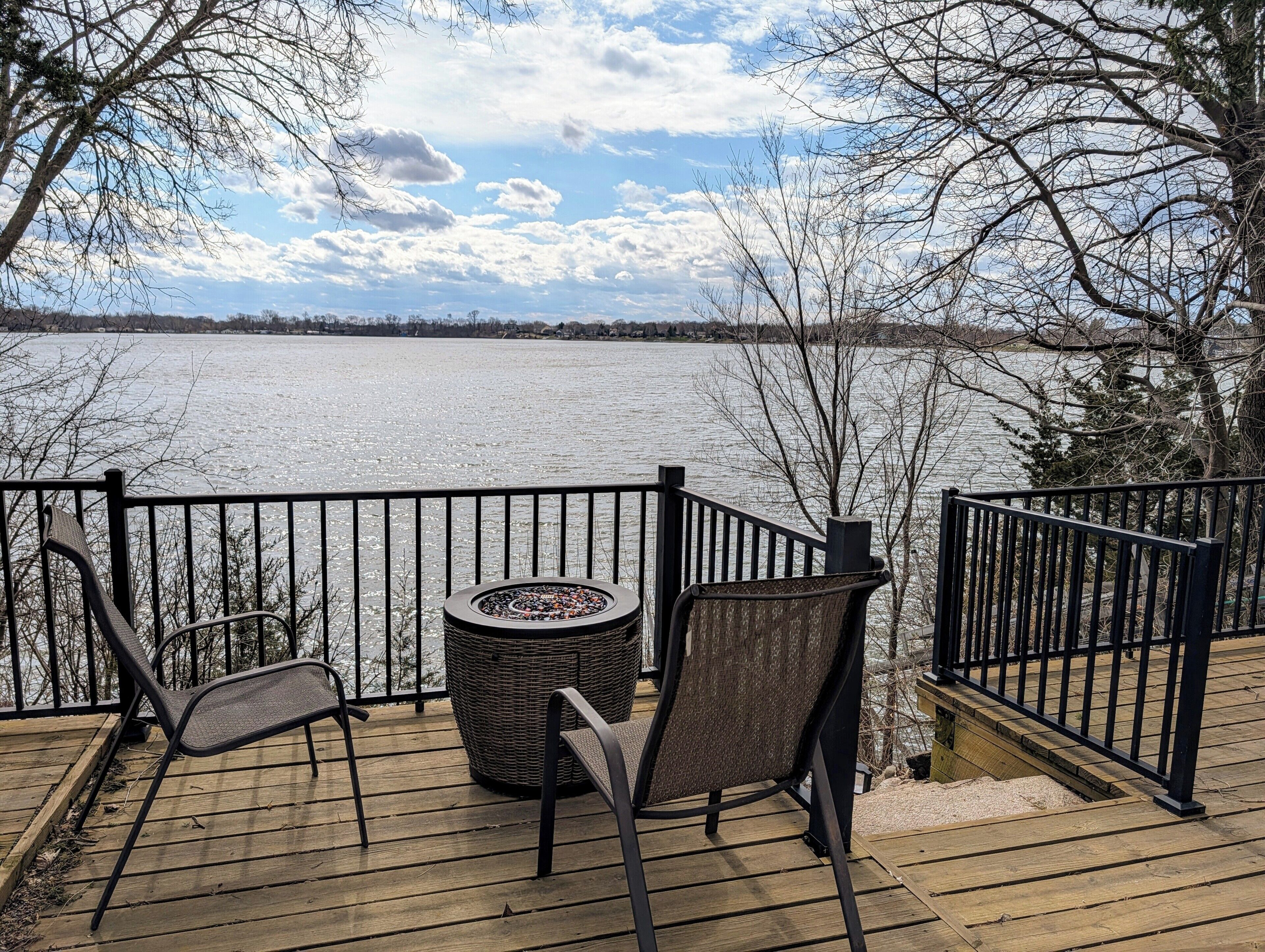 Une terrasse en bois avec deux chaises et une table ronde, donnant sur un lac gelé.