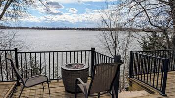 Une terrasse en bois avec deux chaises et une table ronde, donnant sur un lac gelé.