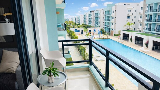 Un balcon donnant sur une piscine, une petite table avec une plante et un canapé.