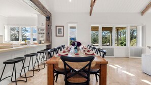 A spacious dining area with a wooden table set for a meal, surrounded by black chairs. - Mulgrave House & Cottage (Bellawongarah)