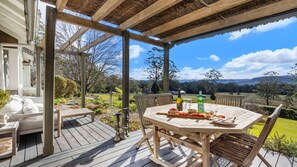 A wooden deck with a table set for dining, overlooking a scenic landscape. - Mulgrave House & Cottage (Bellawongarah)