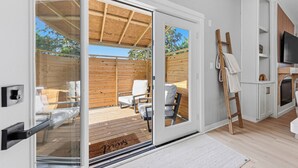 Um interior moderno com uma porta de vidro deslizante que dá para um deck externo, uma televisão e uma escada encostada na parede.