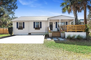 Einbungalow mit Veranda, Auffahrt und einem kleinen Garten.