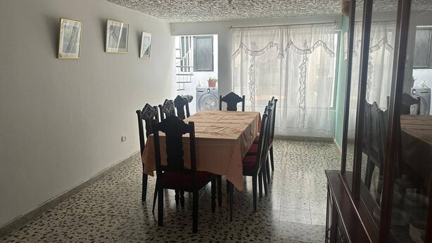 A dining area with a table and chairs, a patterned floor, and a view through a window.