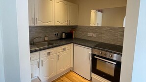 A kitchen with white cabinets, a granite countertop, a stainless steel oven, and a wooden floor. - Stylish Edinburgh Stay | Fast Wi-Fi & Parking (Edinburgh)