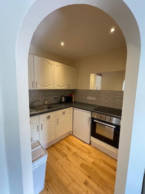 A kitchen with white cabinets, a granite countertop, a stainless steel oven, and a wooden floor. - Stylish Edinburgh Stay | Fast Wi-Fi & Parking (Edinburgh)