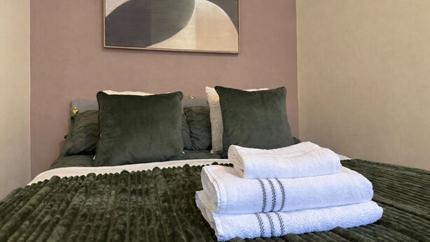 A neatly made bed with pillows, a folded towel, and a blanket. - Stylish Edinburgh Stay | Fast Wi-Fi & Parking (Edinburgh)