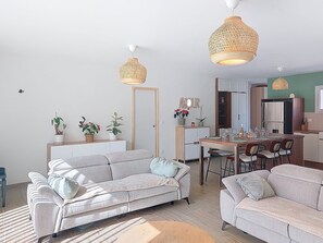 En moderne stue med sofa, spisebord og hængende lamper.