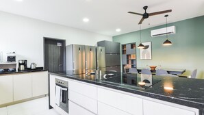 A modern kitchen with a black countertop, stainless steel appliances, and a ceiling fan. - Casa Curie (Monterrey)