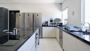 A modern kitchen with stainless steel appliances, a black countertop, and a window providing natural light. - Casa Curie (Monterrey)