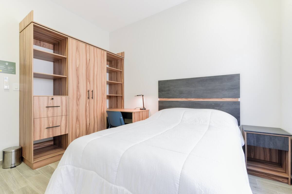 A bedroom with a bed, a desk, a chair, and a wardrobe.