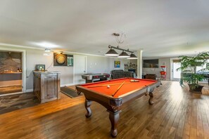 A pool table in a room with wooden flooring, a dartboard, and a fireplace. - Fundy Bay Coastal Estates – Annapolis Valley (Victoria Harbour)