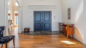 Un vestíbulo amplio con una puerta doble de madera oscura, una pared de acento de piedra y un banco de madera.