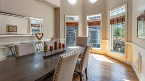 Un comedor con una mesa larga, sillas, velas y una decoración con forma de corazón.