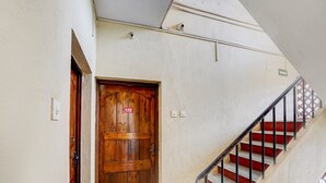 A wooden door with a number plate, a staircase with red steps, and a white wall. - Classic With Balconytownhouse Calangute (Calangute)