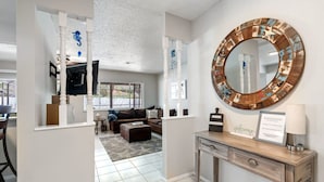 A modern living room with a sofa, coffee table, and a large mirror with a decorative frame. - Palm Harbor Pool Home Near Beaches and Golf (Palm Harbor)