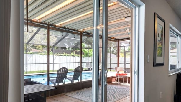 A covered patio area with a pool, chairs, and a table. - Palm Harbor Pool Home Near Beaches and Golf (Palm Harbor)