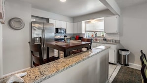 A modern kitchen with granite countertops, stainless steel appliances, and white cabinetry. - Palm Harbor Pool Home Near Beaches and Golf (Palm Harbor)