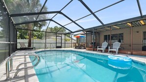 A swimming pool with a glass enclosure, lounge chairs, and umbrellas. - Palm Harbor Pool Home Near Beaches and Golf (Palm Harbor)