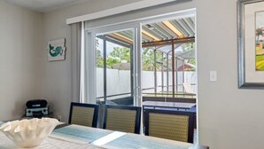 A room with a dining table, chairs, a window, and a view of an outdoor patio. - Palm Harbor Pool Home Near Beaches and Golf (Palm Harbor)