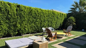 Eine Terrasse mit Liegestühlen, einem kleinen Tisch und einer gepolsterten Bank.
