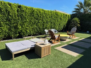 A patio with lounge chairs, a small table, and a cushioned bench. - Serene Oasis in the Desert- Trilogy at the Polo Club (Indio)