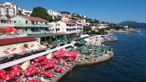 Una cittadina costiera con edifici, un molo con ombrelloni e barche sull'acqua.