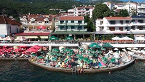 Una località balneare con un porto turistico, ombrelloni sulla spiaggia e edifici con balconi.