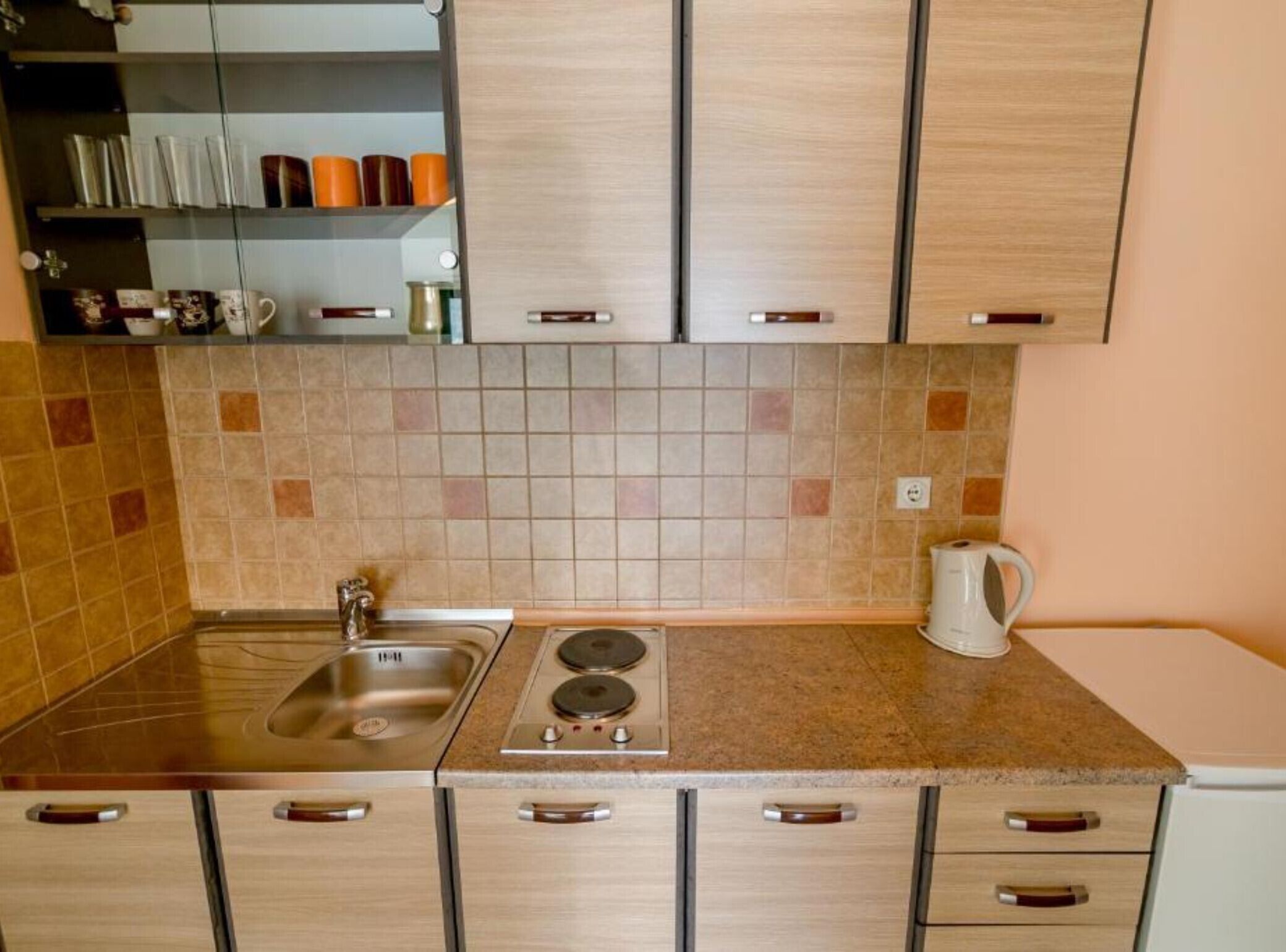 A kitchen with a sink, stove, cabinets, and a coffee maker.