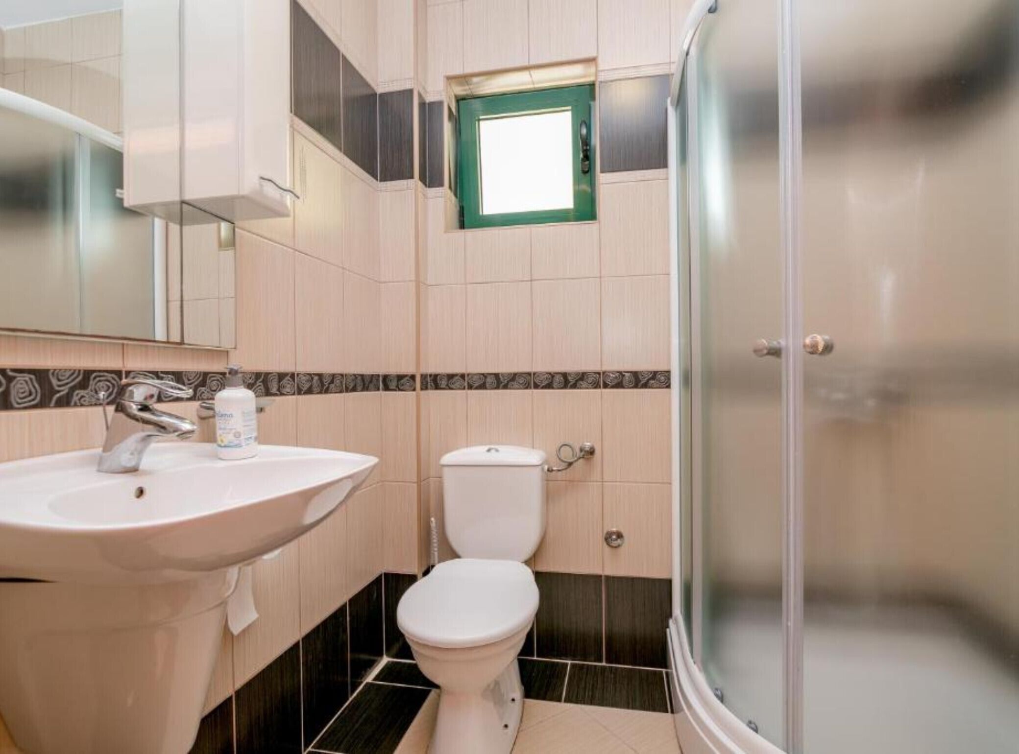A bathroom with a sink, toilet, and glass-enclosed shower.