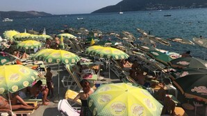 Una platja amb nombrosos para-sols i gandules.