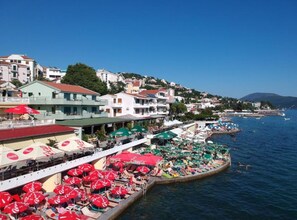 A coastal town with buildings, a pier with umbrellas, and boats on the water. - Amor Residence - One Bedroom Apartment with Terrace and Partial Sea View (6) (Herceg Novi)
