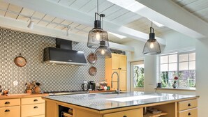 Een moderne keuken met een groot eiland, hanglampen en een decoratieve spatwand.