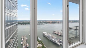 Un edificio alto con vista a un río, un barco grande y un puente.