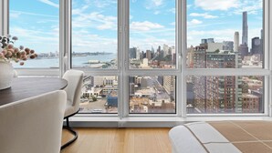 Habitación con amplias ventanas que ofrecen vistas a la ciudad, una mesa de comedor y un sofá.