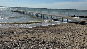 A pier extending into calm waters with a rocky beach in the foreground. - "Danail" - 250m from the sea by Interhome (Juelsminde)