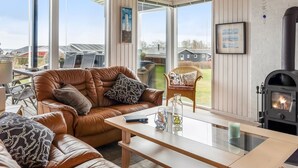 A cozy living room with a leather sofa, a glass coffee table, and a wood-burning stove. - "Danail" - 250m from the sea by Interhome (Juelsminde)