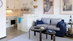 Eine moderne Küche mit weißen Schränken, ein Essbereich mit einem gestreiften Sofa und eine Wand mit einem Picasso-Druck.
